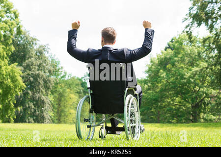 Jeune homme handicapé sur fauteuil roulant avec bras levé Banque D'Images