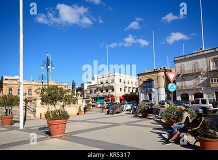 Les touristes se détendre dans la place par le dôme de Mosta avec les bâtiments autour de la place de la Rotonde dans le centre-ville, Mosta, de Malte, de l'Europe. Banque D'Images