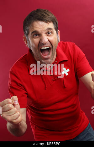 Photo d'un homme Swiss sports fan portant un drapeau suisse shirt et criant pour son équipe. Banque D'Images