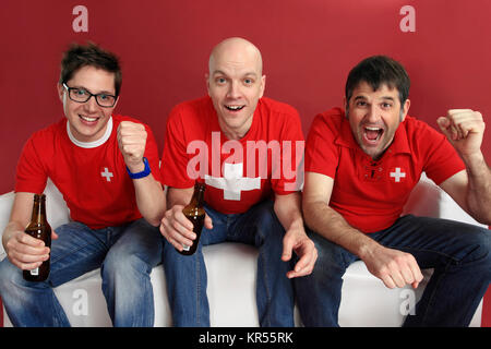 Photo de trois sports fans cheering Suisse mâle pour leur équipe. Banque D'Images