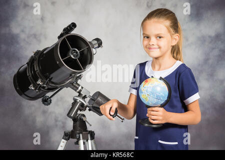 Fille de sept ans est heureux avec le globe dans un télescope réflecteur Banque D'Images