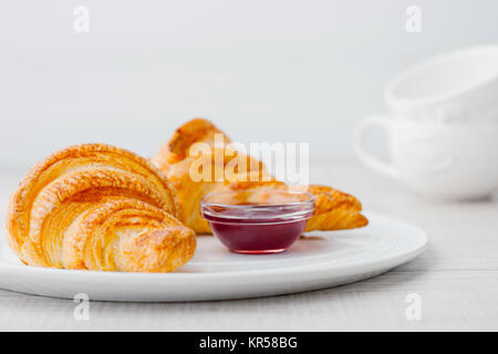 Confiture de petits fruits avec des croissants et deux tasses blanc horizontal trouble Banque D'Images