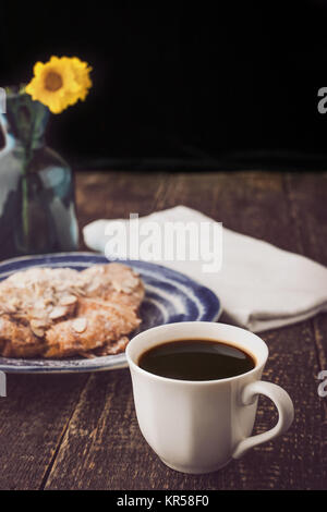 Tasse de café avec un croissant et flou vertical de fleurs Banque D'Images