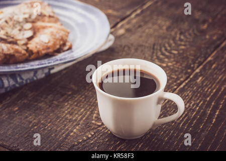 Tasse de café avec un croissant floue sur l'horizontale de la plaque en céramique bleue Banque D'Images