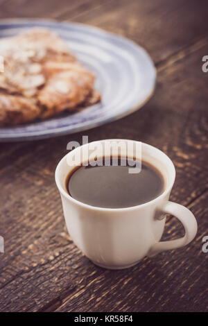 Tasse de café avec un croissant floue sur la verticale de la plaque en céramique bleue Banque D'Images