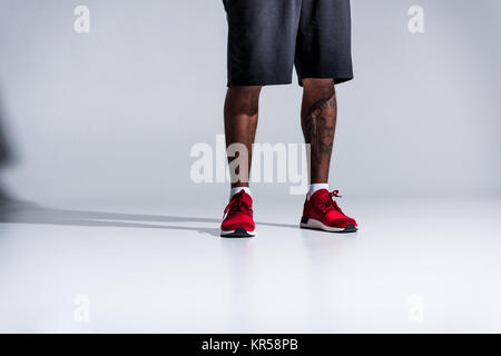 La section basse de african american man en chaussures de sport sur gris Banque D'Images