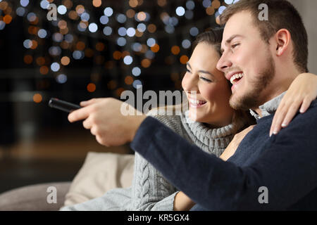 Portrait d'un drôle de couple watching tv assis sur un canapé dans la salle de séjour à la maison dans une nuit d'hiver Banque D'Images