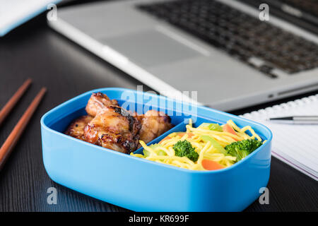 Home cook boîte bento pendant le déjeuner avec ordinateur portable ordinateur bureau Banque D'Images