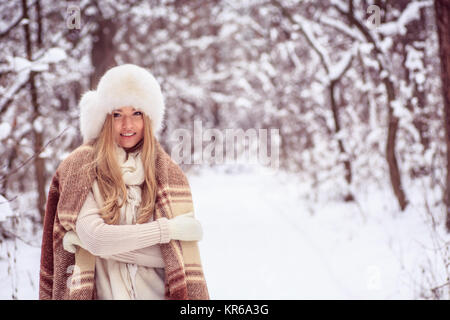 Belle fille blonde est debout dans une couverture dans les bois, de sourires, de grand chapeau sur sa tête et mitaines Banque D'Images