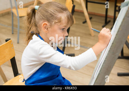 Fille de cinq ans peint sur un chevalet dans le cours de dessin Banque D'Images