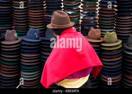 Vue arrière de femme portant chapeau brun et rose lumineux poncho vente de chapeaux de feutre traditionnel équatorien. Banque D'Images