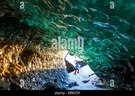 Vue à travers la grotte de glace glaciaire avec alpiniste dans l'arrière-plan. Banque D'Images