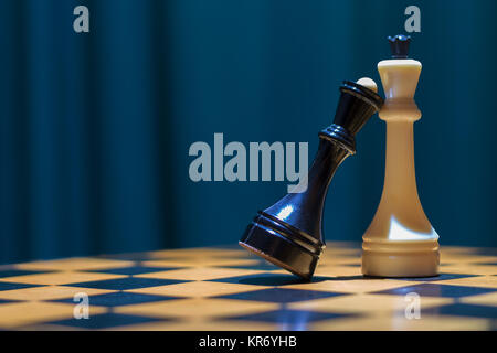 Noir et blanc d'échecs reine roi debout sur un échiquier en bois. La reine noire mit sa tête sur la poitrine pour le roi blanc. Banque D'Images