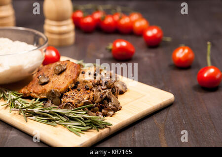 Steak de porc aux champignons, tomates cerise et une plaque avec b Banque D'Images