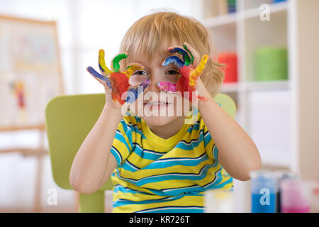 Cute kid gaie avec mains peints dans des couleurs vives Banque D'Images