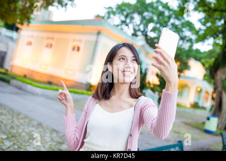 Jeune femme en tenant droit par téléphone mobile dans la ville de Macao Banque D'Images