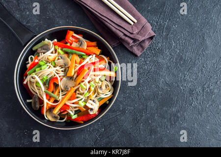 Faire revenir avec les nouilles udon, les champignons et les légumes. La nourriture végétarienne, végétalienne asiatique, repas sautés sur fond noir, copiez l'espace. Banque D'Images