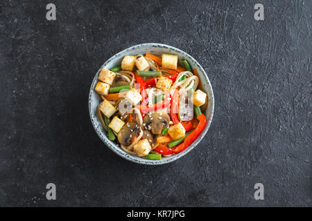 Faire revenir avec les nouilles Udon, tofu, champignons et légumes. La nourriture végétarienne, végétalienne asiatique, repas sautés sur fond noir, copiez l'espace. Banque D'Images