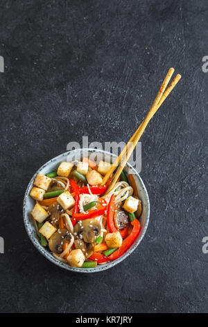 Faire revenir avec les nouilles Udon, tofu, champignons et légumes. La nourriture végétarienne, végétalienne asiatique, repas sautés sur fond noir, copiez l'espace. Banque D'Images