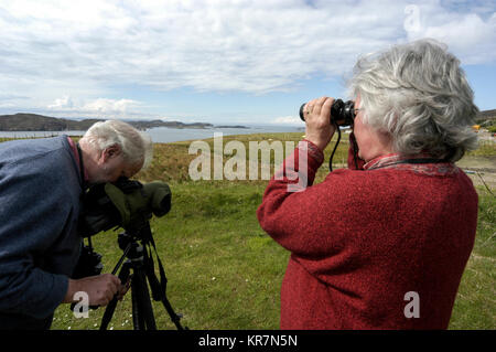 Un couple d'Otter watchers en vacances à l'aide de leurs jumelles, à la recherche de loutres sur la côte ouest de l'Écosse, la Grande-Bretagne. L'Écosse s'attire bien des Banque D'Images