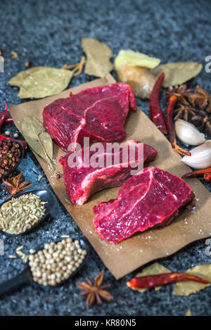 La viande crue. Steak de boeuf sur une planche à découper, de romarin et d'épices. Banque D'Images