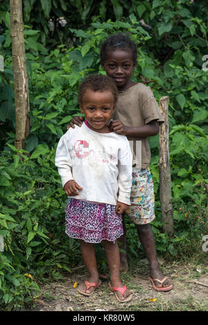 Deux belles jeunes filles malgaches debout près de buissons verts. Madagascar, l'Afrique. Banque D'Images