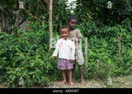 Deux belles jeunes filles malgaches debout près de buissons verts. Madagascar, l'Afrique. Banque D'Images