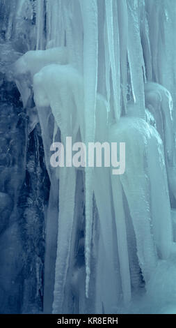 Mur de glace raide glissant vertical avec de longs glaçons dans une grotte. Cascade de glace d'eau. Banque D'Images