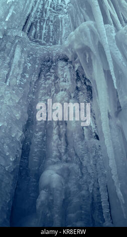 Mur de glace raide glissant vertical avec de longs glaçons dans une caverne. Cascade de glace d'eau. Banque D'Images