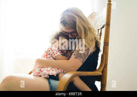 Mère assis sur une chaise à bascule et fille (12-17 mois) Banque D'Images