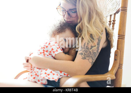 Mère assis sur une chaise à bascule et fille (12-17 mois) Banque D'Images