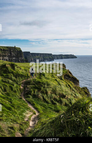 Le Comté de Clare, Irlande, femme marchant le long des falaises de Moher Banque D'Images