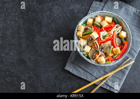 Faire revenir avec les nouilles Udon, tofu, champignons et légumes. La nourriture végétarienne, végétalienne asiatique, repas sautés sur fond noir, copiez l'espace. Banque D'Images