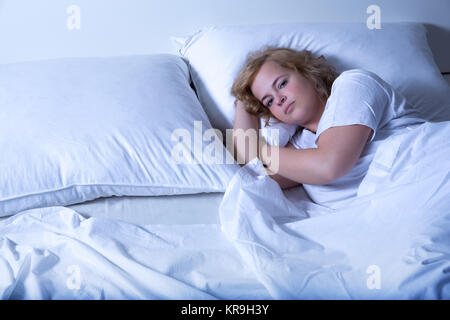 Une jeune femme taille plus dormir dans le lit la nuit. Banque D'Images