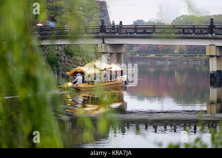 Les personnes qui prennent un tour sur Osaka-jo Gozabune bateau dans le parc du château d'Osaka douves intérieures en passant sous le pont du canal de Gokurakubashi de matin d'automne. Chu Banque D'Images