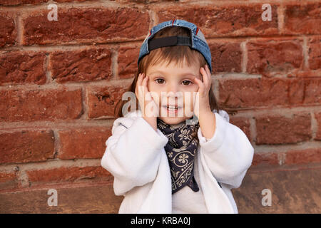 Le hip-hop, de l'enfant portrait of girl in cap libre sur fond de mur de briques. Banque D'Images