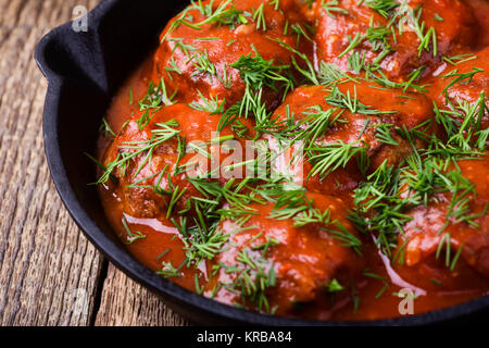 Boulettes de boeuf à la poêle en fonte avec sauce tomate servi avec de l'aneth frais sur le dessus Banque D'Images