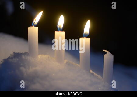 Trois bougies allumées des bougies blanches dans la neige en plein air Banque D'Images