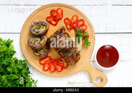 Viande (roll ) avec du fromage, épinards, concombres enrobé de bacon avec de la sauce tomate sur un fond de bois blanc. La vue supérieure. Maison de vacances menu. Banque D'Images