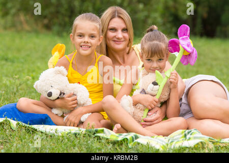 Jeune mère assise sur un pique-nique dans une clairière avec deux filles Banque D'Images