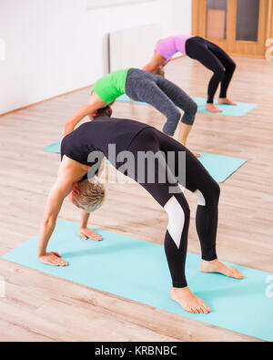 Trois jeunes filles pratiquant le yoga, Setuasana / pose du pont Banque D'Images