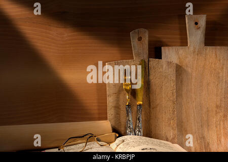 Mur en bois avec deux planches à découper, vieille argenterie, livre de recettes, verres et rouleau à pâtisserie. Concept d'une cuisine rustique Banque D'Images