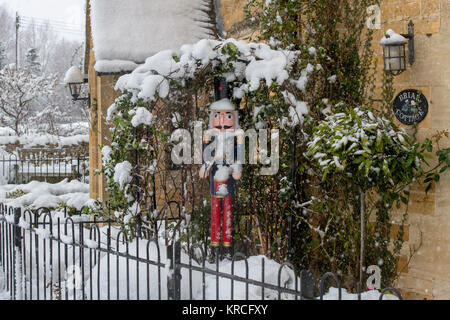 Le batteur en bois Noël figure décoration dans le jardin de devant d'un chalet dans la neige. Lower Slaughter, Cotswolds, Gloucestershire, Angleterre Banque D'Images