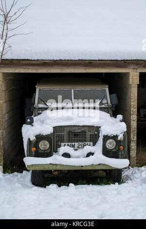 Vintage 1969 Land Rover couvertes de neige garé dans un garage ouvert. Chedworth, Cotswolds, Gloucestershire, Angleterre Banque D'Images