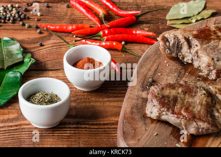 Deux steak cuit avec différents condiments et le couteau sur la table. Banque D'Images