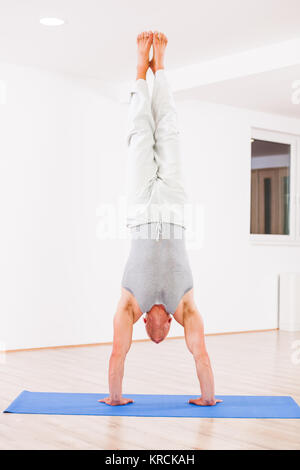 Hot man practicing yoga, Vrksasana / Handstand poser Banque D'Images