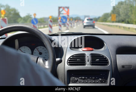 Conduire une voiture sur une route avec des travaux et avec d'autres véhicules floue devant lui Banque D'Images