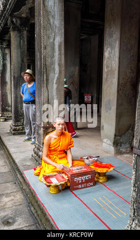 Jeune moine en robe safran se trouve à Angkor Wat, un complexe de temple près de Siem Reap au Cambodge, le plus grand monument religieux du monde Banque D'Images