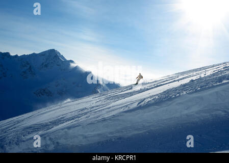 La descente des skieurs de pente sur un fond de ciel bleu et les montagnes Banque D'Images