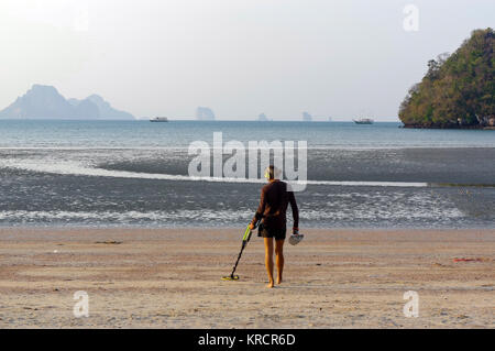 Chasseur de trésor avec détecteur de métal sur le sunrise beach Banque D'Images